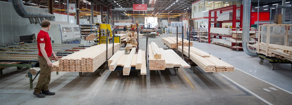 Stacks of milled lumber on the factory floor with a worker in a red shirt
